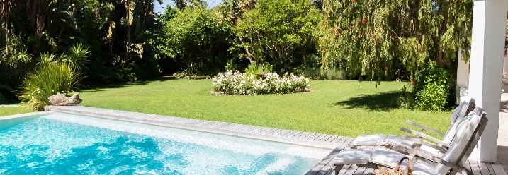 Rechteckiger Pool mit Holzterrasse im Garten